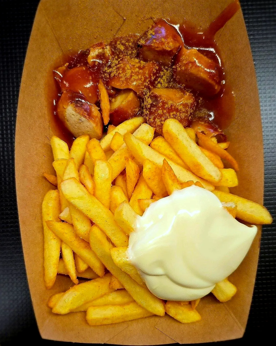 Currywurst mit Pommes und Mayonnaise in der Pappschale